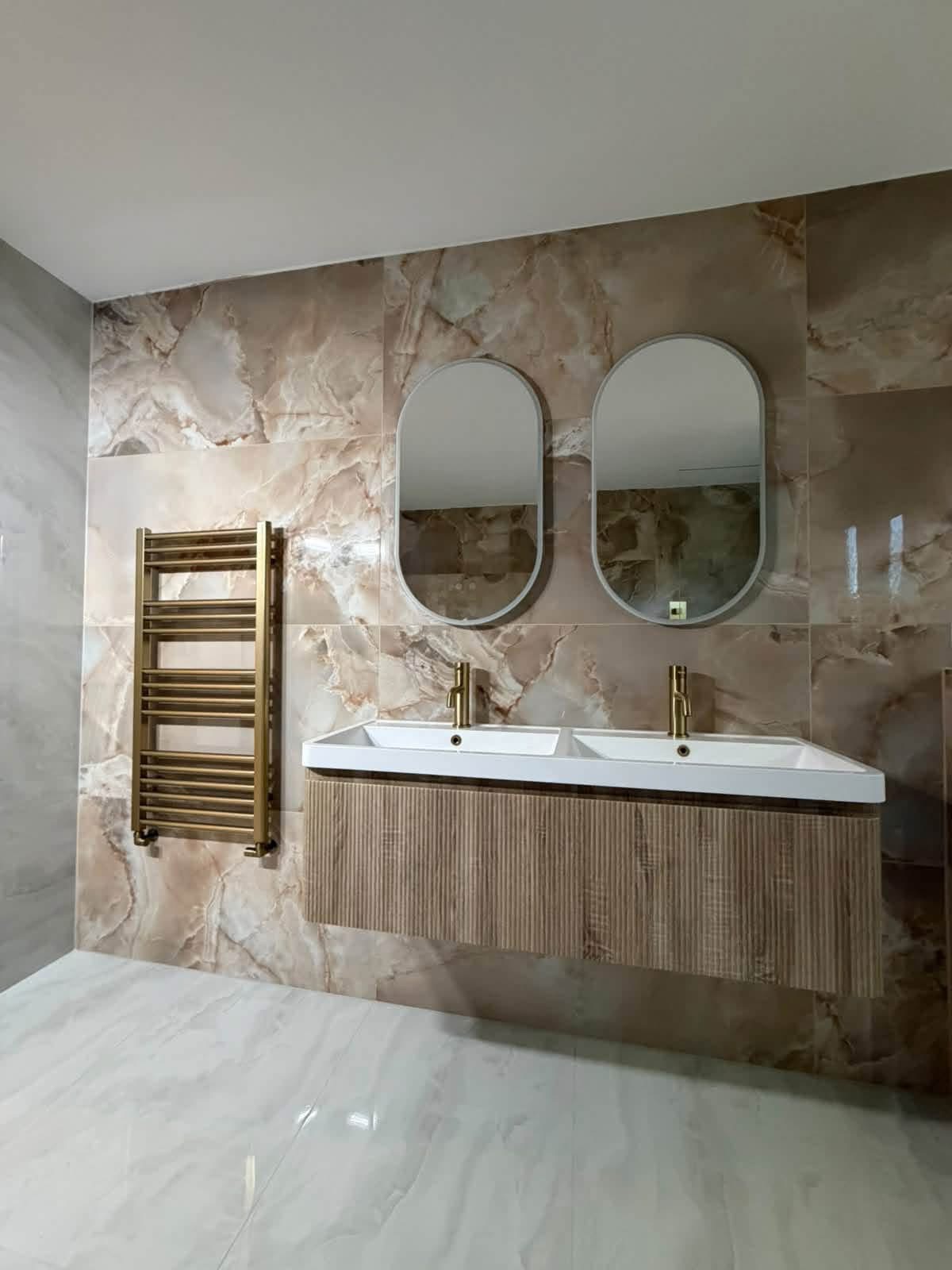 Double vanity with oval mirrors and gold fittings