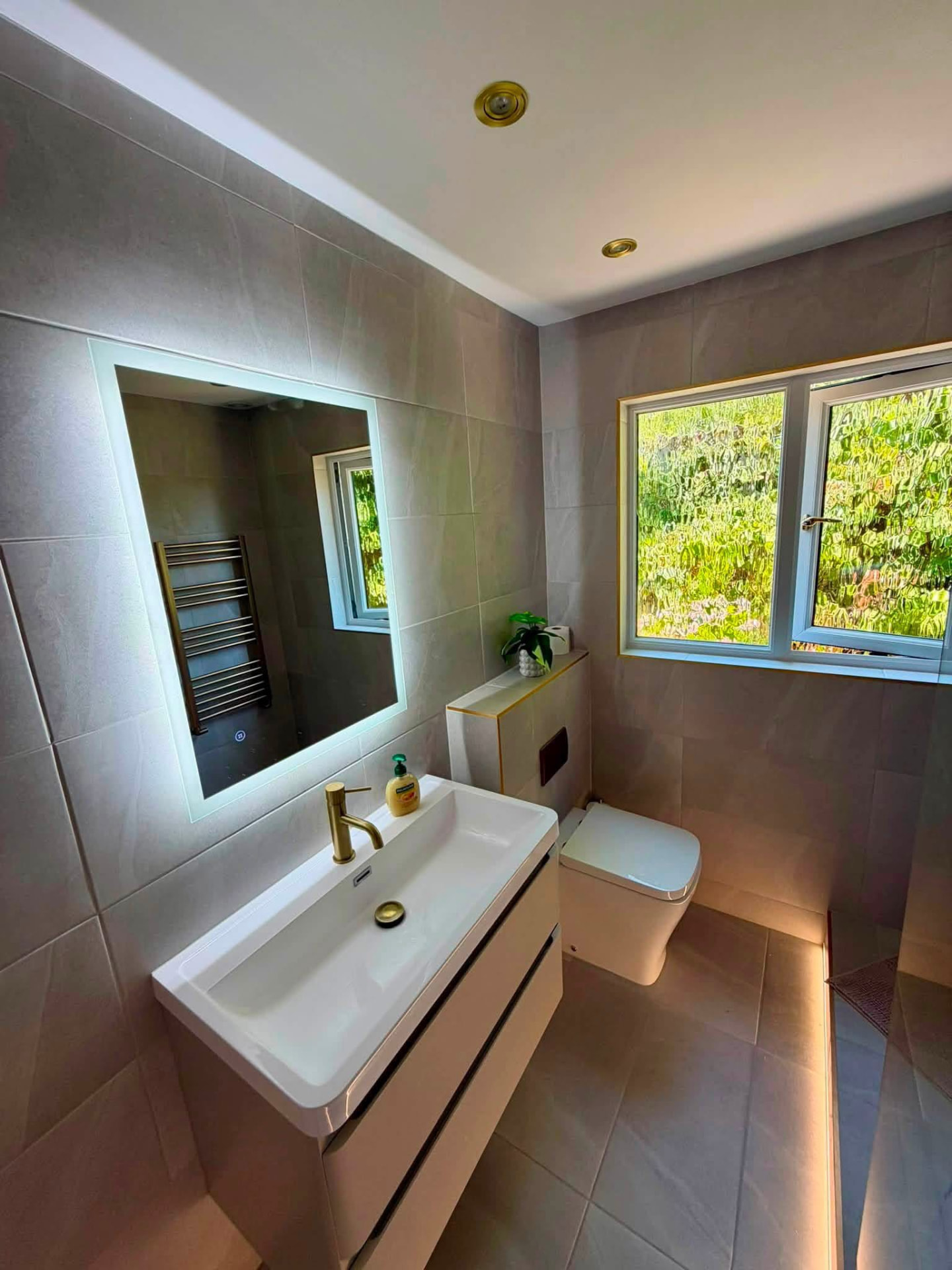Bathroom with backlit mirror and wall-hung vanity
